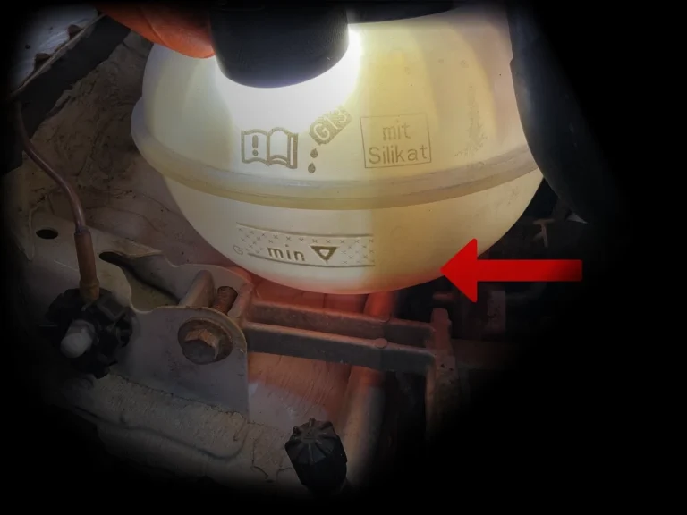 Audi VW Service A red arrow points to the minimum fill line on a translucent car coolant reservoir, illuminated by a flashlight, with engine components visible around it. Reflex Tuning, Hookett NH