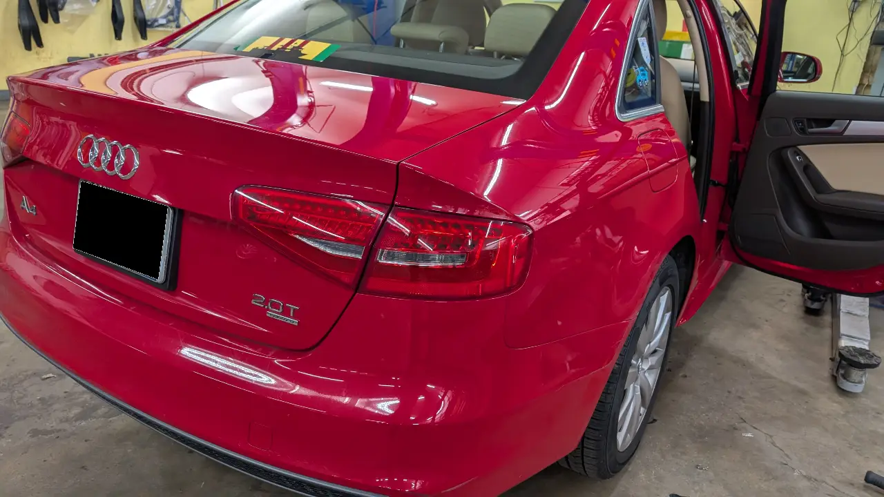 Audi VW Service A bright red Audi sedan, viewed from the rear side in a garage. The drivers door is open and license plate is blacked out. The badge indicates it is a 2.0T model. Reflex Tuning, Hookett NH