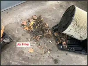 Audi VW Service A dirty air filter removed from its casing sits beside a pile of dust, dirt, and dry leaves on a concrete floor. The label Air Filter is visible near the filter. Reflex Tuning, Hookett NH