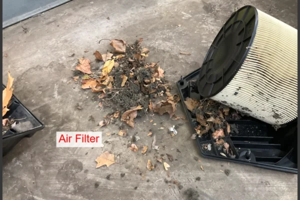 Audi VW Service A dirty air filter removed from its casing sits beside a pile of dust, dirt, and dry leaves on a concrete floor. The label Air Filter is visible near the filter. Reflex Tuning, Hookett NH