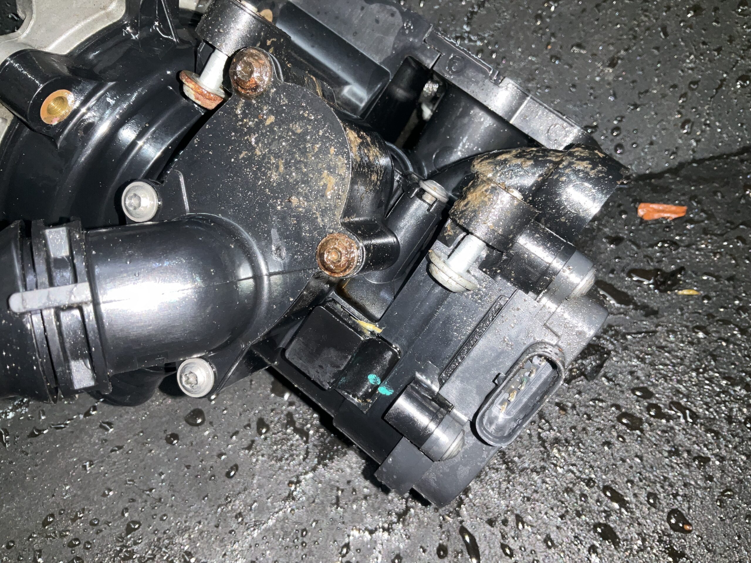 Failed water pump and thermostat housing removed from a 2018 Audi S3 showing coolant leak staining at Reflex Automotive